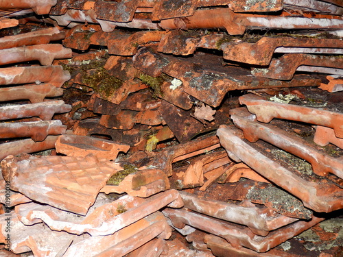 Old terracotta tiles removed from a workshop roof, covered in grime and lichen