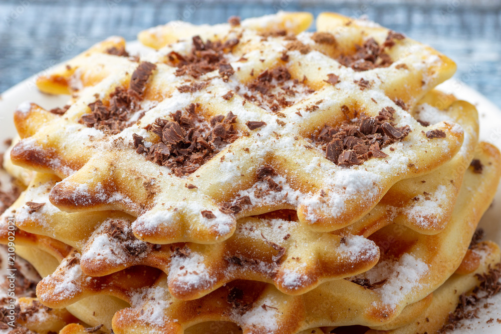 Homemade waffles with chocolate and powdered sugar in close up view