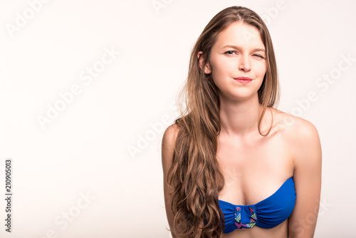 A girl in a blue swimsuit on a light background