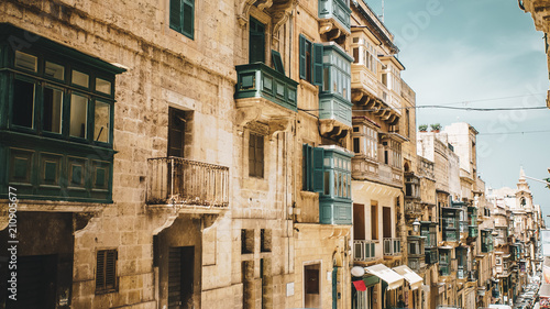 Typical street with traditional balconies in historical center of Valletta in Malta on sunny day.