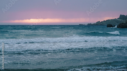 Beautiful pink and purple sunset on the beach. Sea, ocean with waves at dusk.