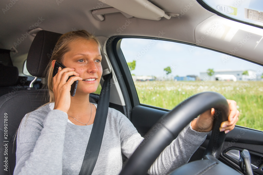 Junge Frau telefoniert beim Autofahren