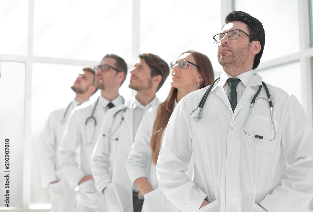 group of doctors standing in a row and looking at a copy space group of doctors standing in a row and looking at a copy space