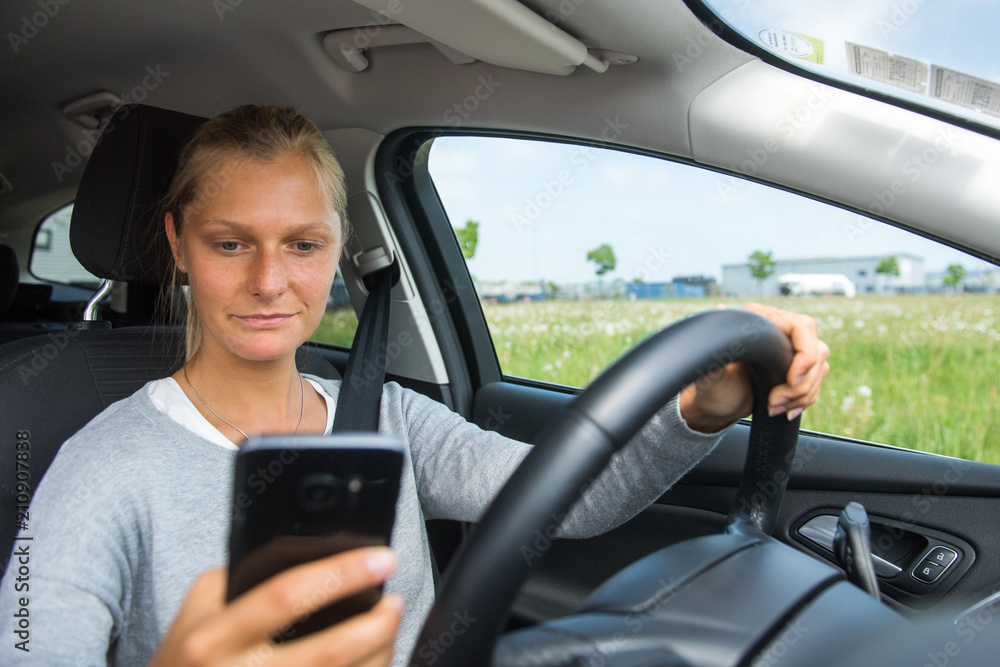 Junge Frau tippt SMS beim Autofahren Junge Frau tippt SMS beim Autofahren