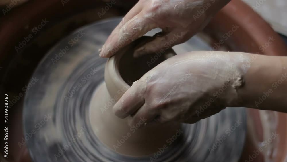 Making of cup on potter's wheel. Female hands makes, forming ware from wet clay Making of cup on potter's wheel. Female hands makes, forming ware from wet clay