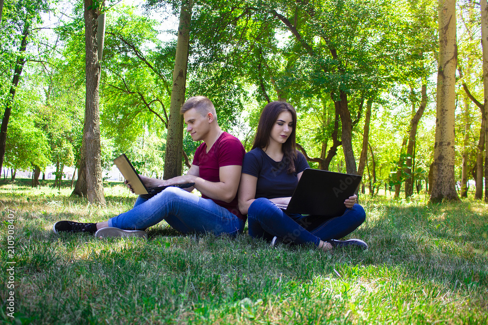 The guy and the girl work in laptops on the nature. The guy and the girl work in laptops on the nature.