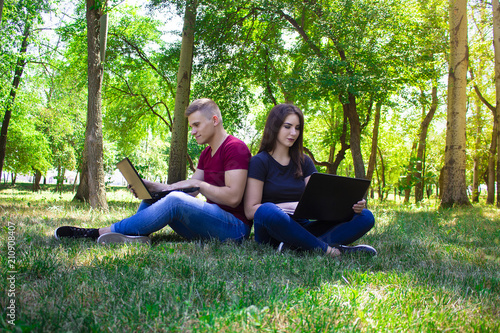 The guy and the girl work in laptops on the nature.