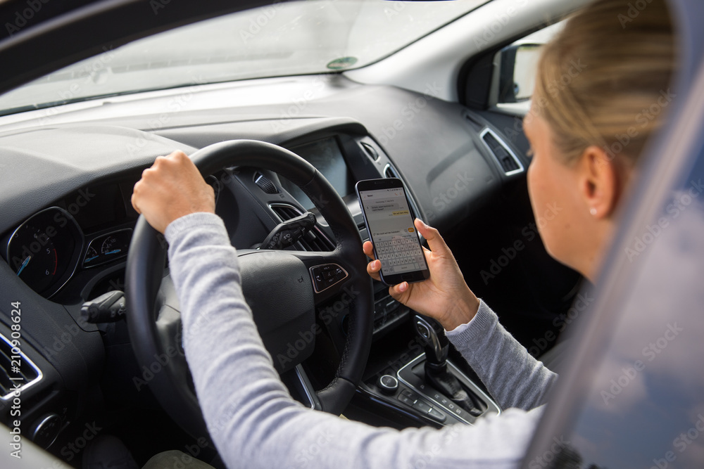 Junge Frau schreibt während der Autofahrt eine SMS