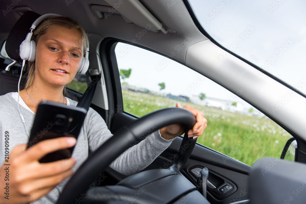 Junge Frau hört während der Fahrt Musik und schreibt eine SMS Junge Frau hört während der Fahrt Musik und schreibt eine SMS