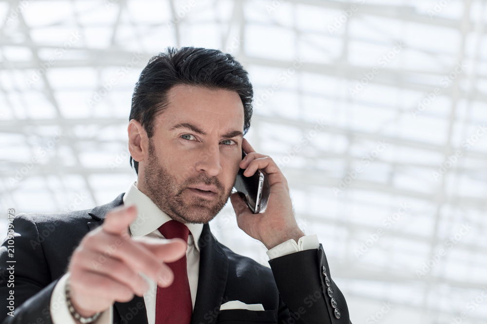 businessman talking on the phone and pointing at you businessman talking on the phone and pointing at you
