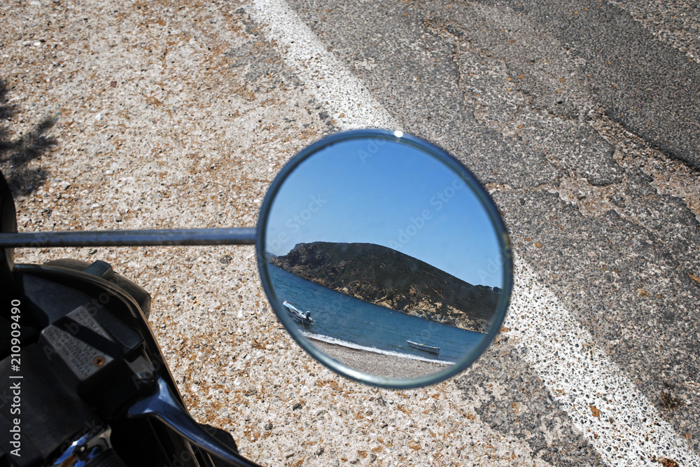 A reflection of a beach from a scooter side mirror in summer time