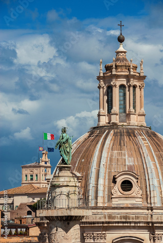 Ancient Trajan Column with St Peter statue and baroque Church of Most Holy Name of Mary and Quirinal Hill 'Towers of the Winds' among clouds in Rome