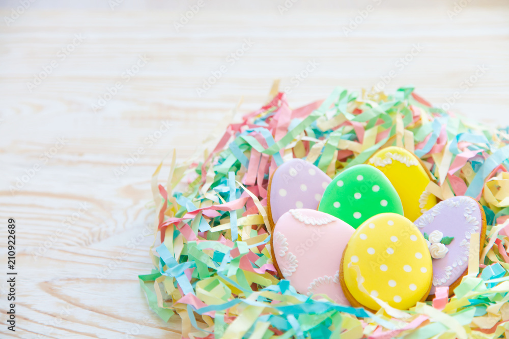 Fototapeta premium Easter homemade gingerbread cookie. Bird's nest Easter made from colored paper. The background is aged light wood.