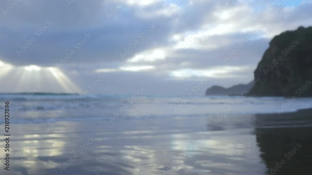 Soft focus background of gentle waves on beach at dusk with streaking shafts of heavenly golden light Soft focus background of gentle waves on beach at dusk with streaking shafts of heavenly golden light