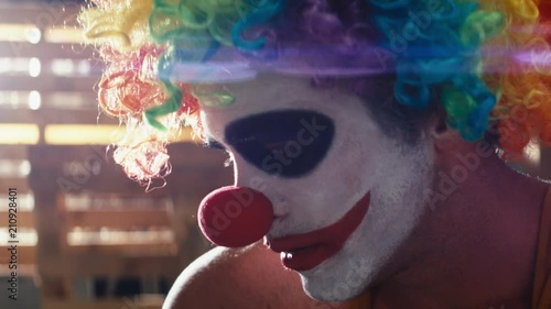 Close up sad crazy clown smoking a cigarette with anamorphic lens flare