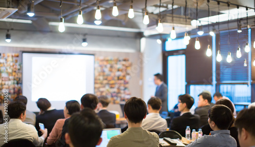 Presenter Presenting on Stage at Conference Meeting. Professional Lecture. Blurred De-focused Unidentifiable Presenter and Audience. Corporate Executive Manager Speaker. People Attendees