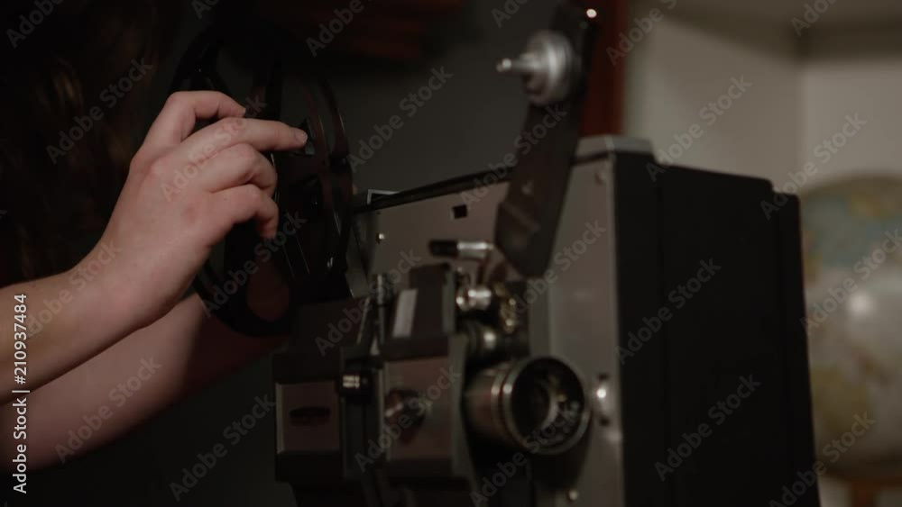 Person putting wheel on old projector. Person putting wheel on old projector.