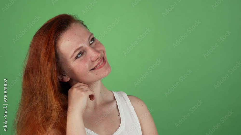 Portrait of a gorgeous happy young red haired woman smiling dreamily, looking away at the copy space on the side. Attractive female daydreaming, posing on green chromakey. Portrait of a gorgeous happy young red haired woman smiling dreamily, looking away at the copy space on the side. Attractive female daydreaming, posing on green chromakey.