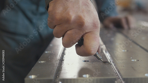 Foto Male hands makes chamfering removing burrs on metal panel with a scraper