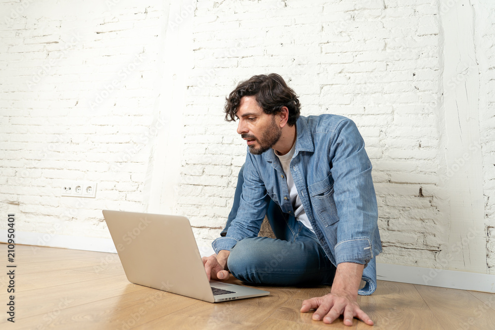 freelance hipster working from home on a laptop with white brick wall background. freelance hipster working from home on a laptop with white brick wall background.