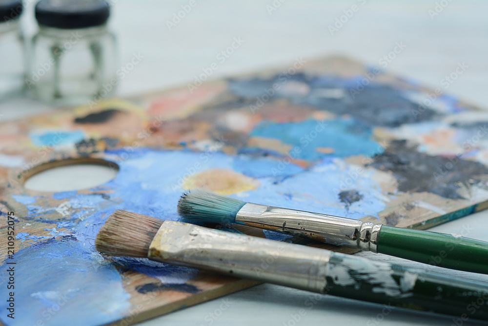 Artist's palette with colorful oil paint strokes and paintbrushe