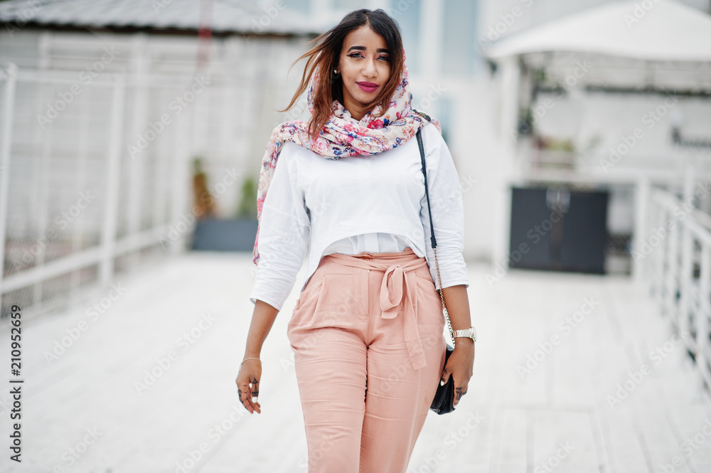 Fototapeta premium Fashion arabian girl at white blouse and peach pants posed outdoor. Stylish muslim woman.
