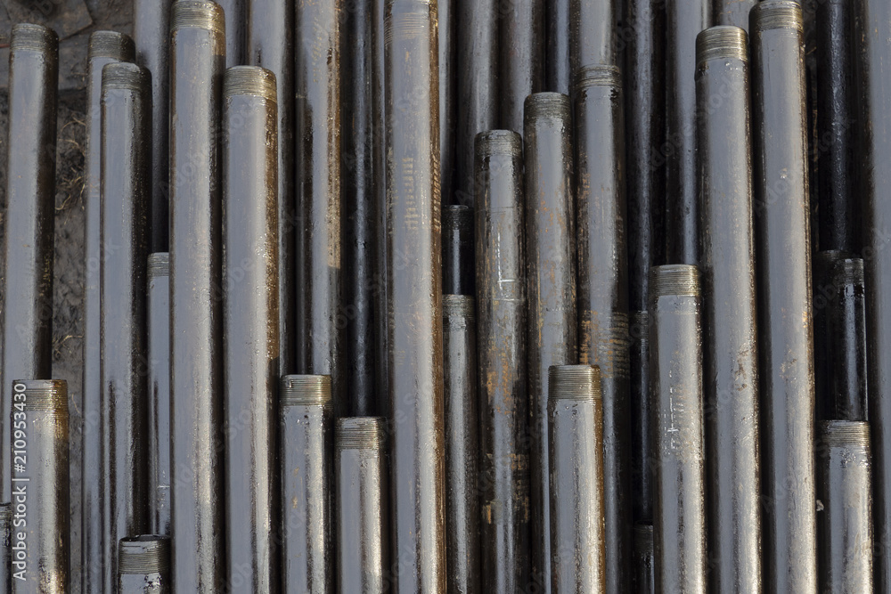 Oil Drill pipe. Rusty drill pipes were drilled in the well section. Downhole drilling rig. Laying the pipe on the deck. View of the shell of drill pipes laid in courtyard of the oil and gas warehouse. Oil Drill pipe. Rusty drill pipes were drilled in the well section. Downhole drilling rig. Laying the pipe on the deck. View of the shell of drill pipes laid in courtyard of the oil and gas warehouse.