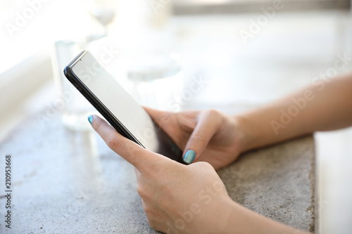 Close up on woman hand holding smartphone trading stock and data in coffee shop background business concept