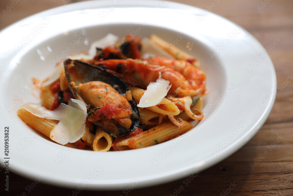Penne pasta tomato sauce arabiata with seafood on wood background vintage style Penne pasta tomato sauce arabiata with seafood on wood background vintage style