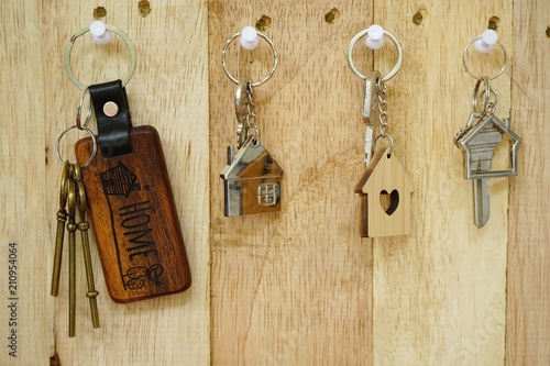 House key with wooden home keyring hanging on wood board background, property concept, copy space