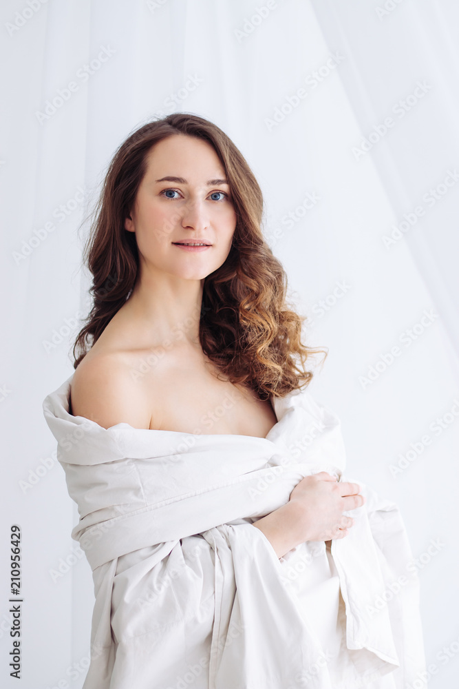 portrait of young woman in white blanket with open shoulders portrait of young woman in white blanket with open shoulders
