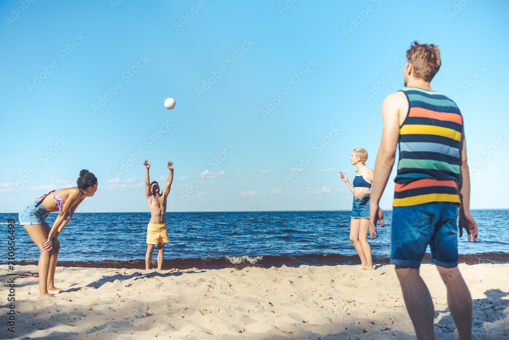 interracial friends playing volleyball together on sandy beach interracial friends playing volleyball together on sandy beach