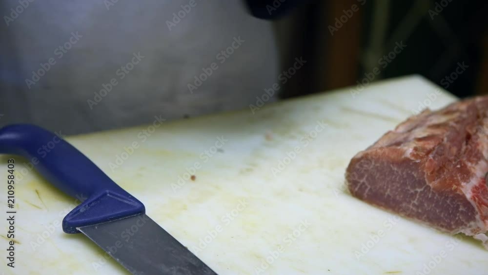4K, Butcher in shop trimming pork loin, using knife to cut meat in a grocery. Iberian pork shopping in spanish supermarket. Woman knives the piece of corpse on cutting table and cuts into pieces -Dan 4K, Butcher in shop trimming pork loin, using knife to cut meat in a grocery. Iberian pork shopping in spanish supermarket. Woman knives the piece of corpse on cutting table and cuts into pieces -Dan