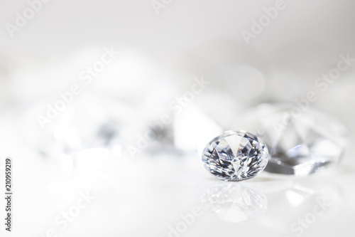 Diamant auf weiß mit Spiegelung vor weißem Hintergrund, mehrere Diamanten in der Unschärfe, Edelsteine mit Textfreiraum photo