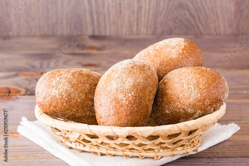Fresh rye buns in a basket on a wooden table