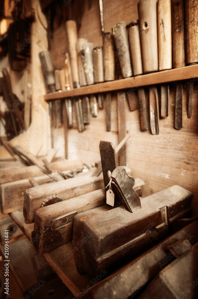 Vintage colored image of carpenter tools on the wall and bench of a dusty workshop
