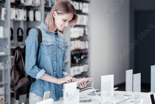 Calm woman. Pretty relaxed young woman looking attentively at wonderful gadgets in a shop