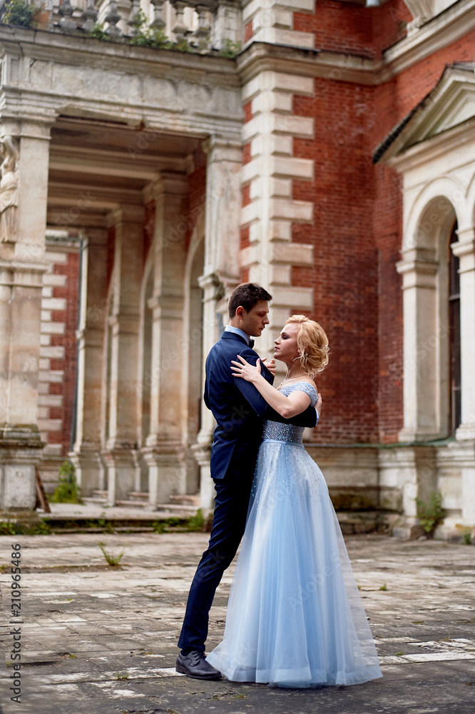 The bride and groom dancing around the columns of the old estate. A tall groom, and a bride with blond hair. Blue wedding dress. Wedding walk and photo shoot The bride and groom dancing around the columns of the old estate. A tall groom, and a bride with blond hair. Blue wedding dress. Wedding walk and photo shoot