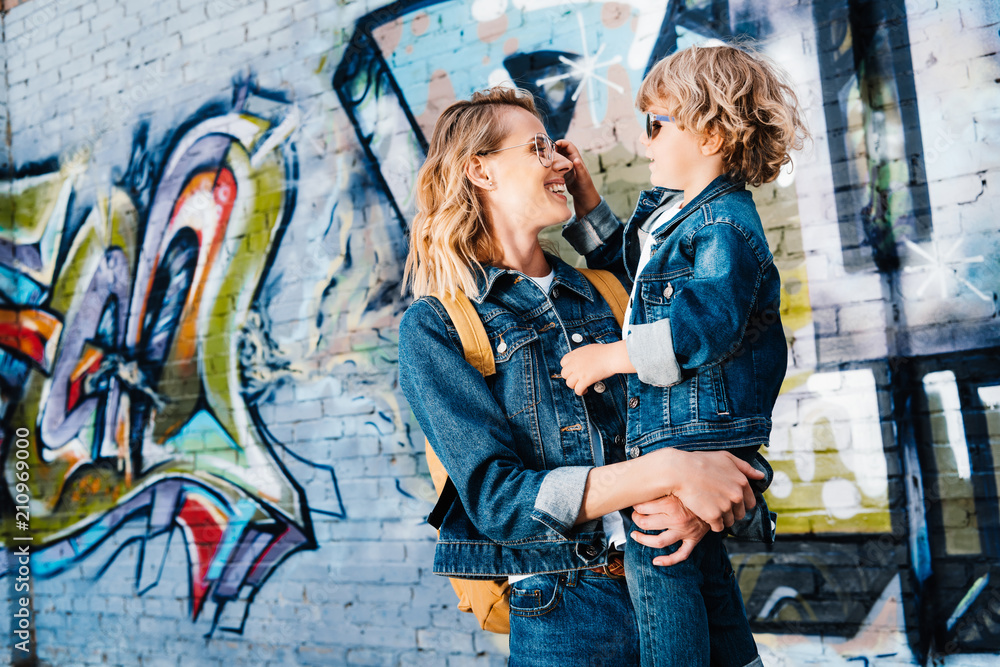 Obraz premium szczęśliwa matka trzyma syna i patrząc na siebie na ulicy