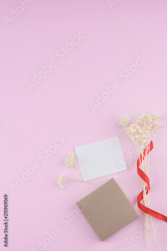 Blank white card, brown gift box decorate with white dried flowers bouquet on pastel pink background with copy space © nathiyai