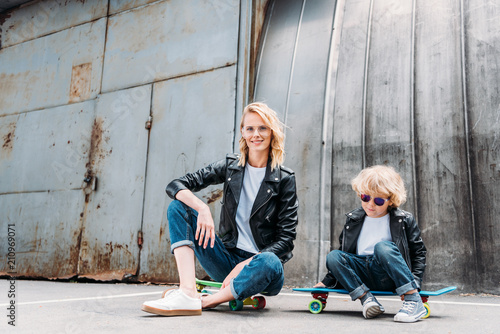 mother and son sitting on skateboards on street