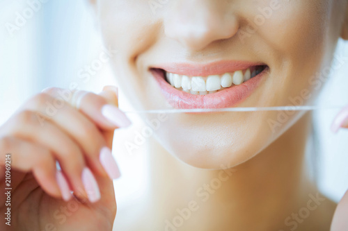 Health and Beauty. Close up. Beautiful Young Girl With White Teeth Cleans Teeth With Dental Floss. A Woman With A Beautiful Smile. Tooth Health