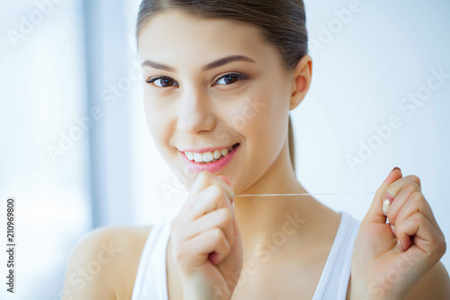 Health and Beauty. Beautiful Young Girl With White Teeth Cleans Teeth With Dental Floss. A Woman With A Beautiful Smile. Tooth Health