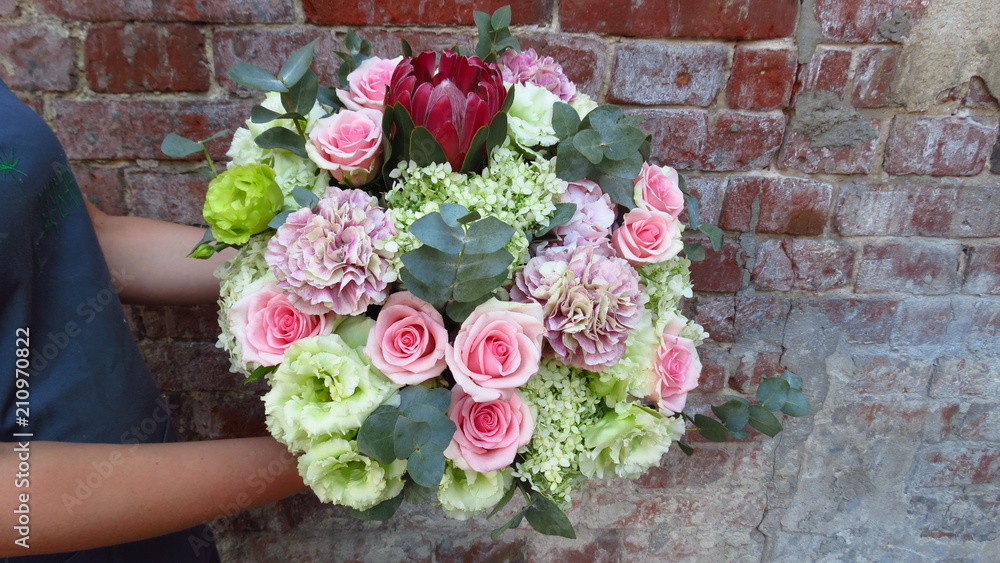 Bouquet with bright flowers on a brick wall background. Work in a flower shop