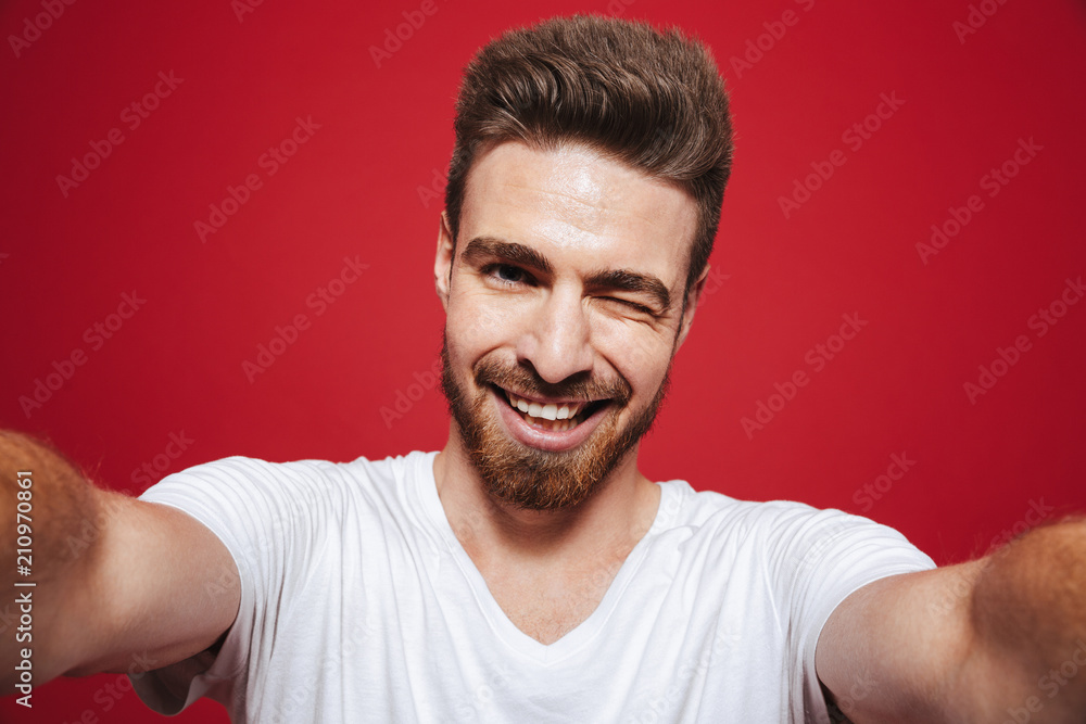 Obraz premium Portrait of a cheerful young bearded man winking