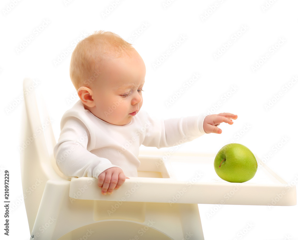 Beautiful child sitting in a high chair with a green Apple on a white background. Beautiful child sitting in a high chair with a green Apple on a white background.