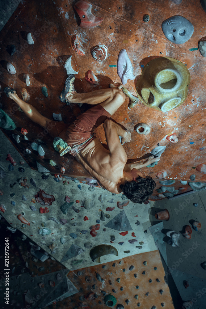 Fototapeta premium Free climber young man climbing artificial boulder indoors