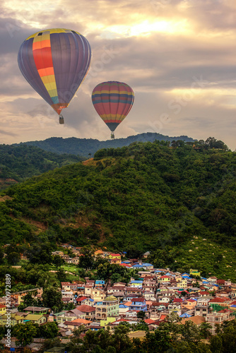 hdr shot of colorful hotair balloon flying over city in the mountain during sunset giving colorful sky color (selective focus and tone adjustment in post process) © Sharpnaja
