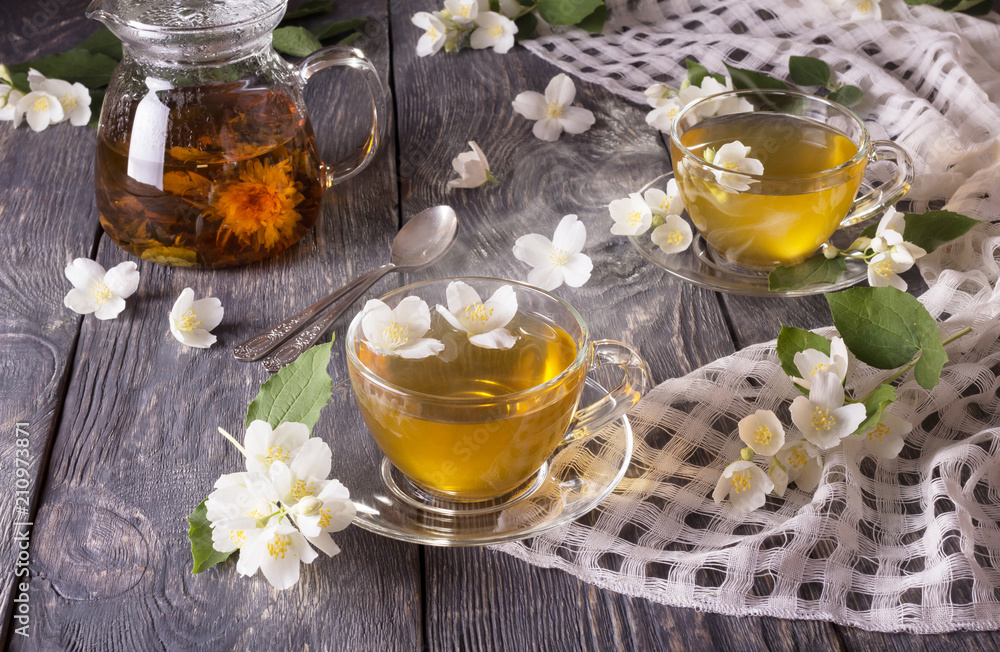 Steam over Cup of hot tea with Jasmine, flowers are scattered on gray surface Steam over Cup of hot tea with Jasmine, flowers are scattered on gray surface