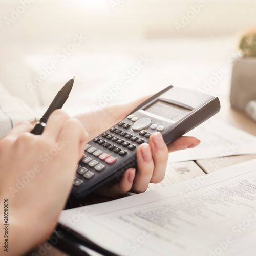 Student girl calculating with calculator and writing notes
